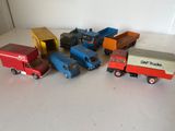 Plusieurs camions miniatures sont alignés sur une surface blanche