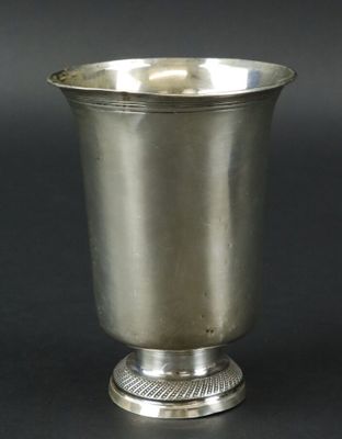 une coupe ancienne en argent posée sur un socle, sur fond noir