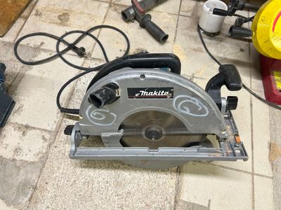 a circular saw sitting on the floor next to other tools