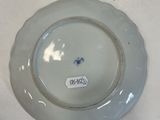 a plate with a blue flower on it sitting on a table