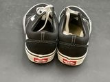 pair of black and white vans slip - ons on a gray surface