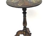 une petite table avec un plateau peint, reposant sur un piètement à trois pieds