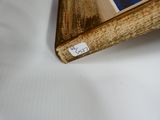 une photo représentant un cadre en bois posé sur une surface blanche