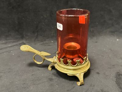 un bougeoir en verre rouge sur lequel est posée une cuillère