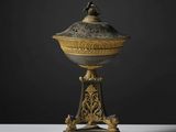 une urne richement décorée d'or et d'argent, surmontée d'un oiseau