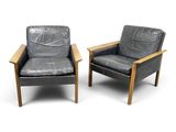 pair of black leather lounge chairs with wooden arms