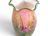 a pink and green vase sitting on a white surface