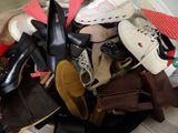 de nombreuses paires de chaussures empilées les unes sur les autres sur un lit