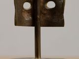 a bronze sculpture of a face on a wooden stand