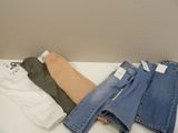 three pairs of women ' s jeans sitting on top of a white table