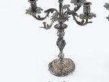 a silver candelab with three candles and a small figurine next to it