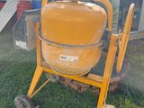a yellow cement mixer sitting in the grass