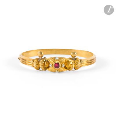 a close up of a gold ring with a red stone in the middle