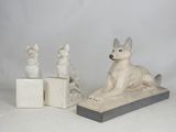 three statues of cats and a dog sitting on a block