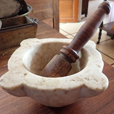 un mortier muni d'un manche en bois, posé dans un saladier sur une table