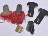 four pairs of shoes, a belt, and a purse are laid out on a white surface