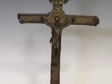 un crucifix ancien en bronze posé sur un socle en bois