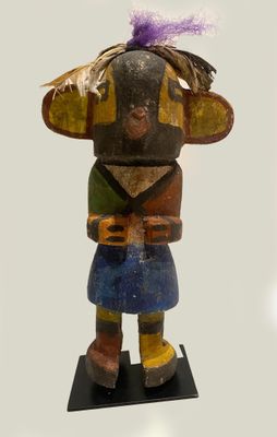 a wooden statue of a woman with a purple feather on her head