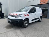 La camionnette blanche est garée devant un immeuble orné d'une bande rouge et blanche.