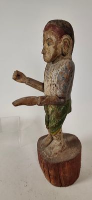une vieille figurine en bois représentant un singe sur une souche d'arbre