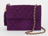 un sac Chanel violet avec une chaîne dorée et des pompons
