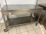 a stainless steel work table with wheels on the floor