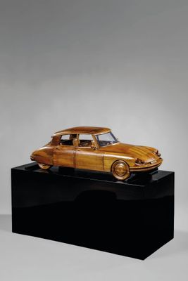 une photo d'une maquette en bois de voiture posée sur un socle noir