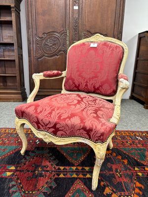 une chaise rouge et dorée posée sur un tapis dans une pièce
