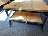 a coffee table with a wooden top on wheels on a carpeted floor