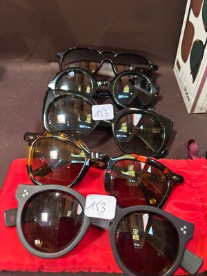 de nombreuses paires de lunettes de soleil posées sur un tissu rouge, sur une table