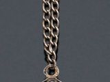 silver and blue enamel charm with a chain on a gray background