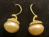 a pair of earrings with pearls on them sitting on a black surface