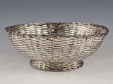 an antique silver plated bowl on a stand on a white surface