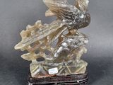 statue of a bird on a rock on a black surface