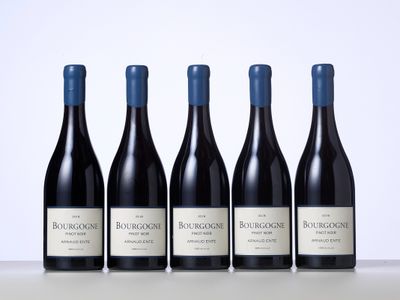 quatre bouteilles de vin rouge sont alignées sur une table