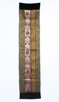 une écharpe rayée de marron et de rouge accrochée à un mur blanc