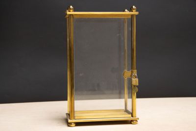 une image représentant une horloge en laiton avec une vitre de protection, posée sur une table