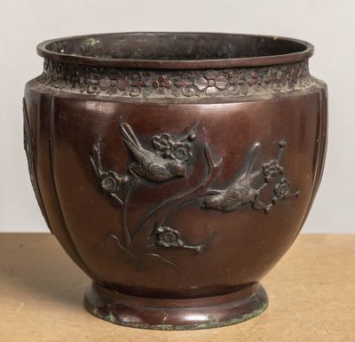 a brown vase with a bird and flowers on it