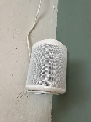 a white speaker on the wall next to a white wall