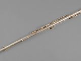 an old silver flute with a wooden handle on a gray surface
