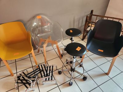 Plusieurs chaises et tabourets sont disposés sur le carrelage d'une pièce