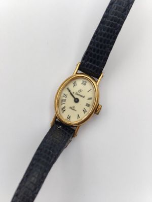 gros plan d'une montre sur une surface blanche avec un bracelet noir