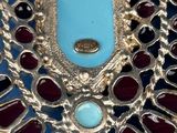 a close up of a necklace with a turquoise stone in the center