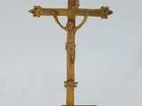 a gold cross on a black stand with a white background