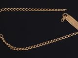 a close up of a gold chain bracelet on a black background