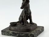 statue en bronze représentant un chien assis sur un socle en marbre