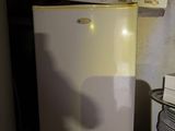 a small white refrigerator in the corner of a room