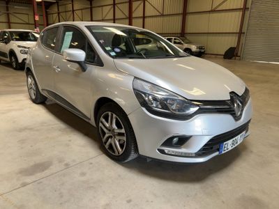 La voiture argentée est garée dans un garage, avec d'autres voitures en arrière-plan.