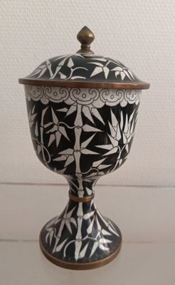 black and white ceramic urn with gold accents on a white table
