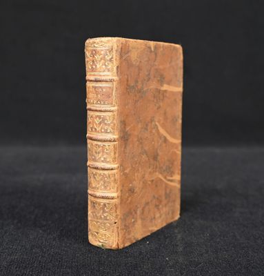 an old book sitting on top of a black cloth covered table